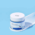 ROUND LAB Birch Juice Moisturizing Cream 80 ml jar on a cream swatch against a blue background — manufacturer photograph